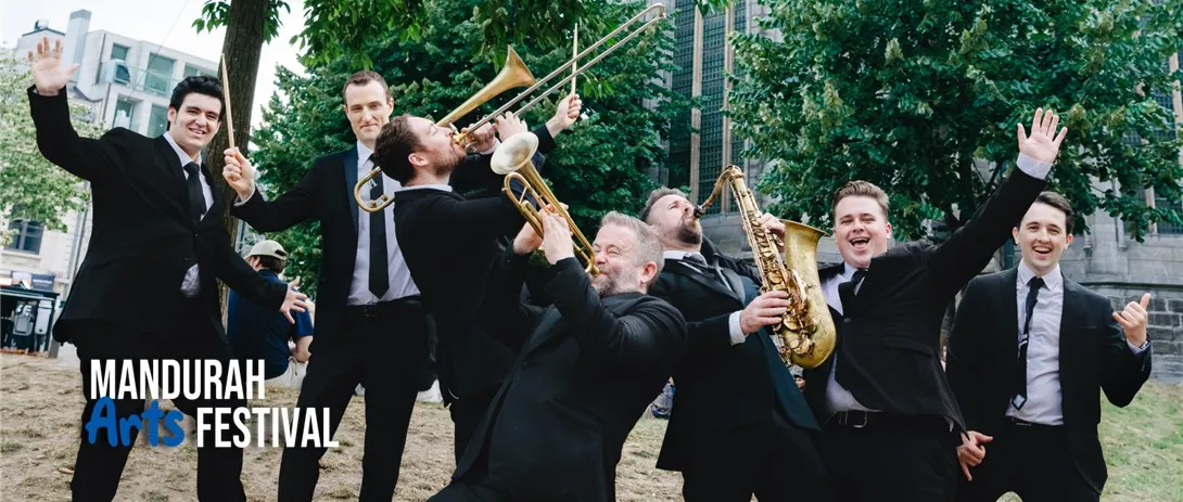 a group of men in suits stand with energetic positions, holding various brass instruments